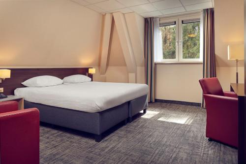 a hotel room with a bed and two chairs at Hotel De Werelt Garderen in Garderen