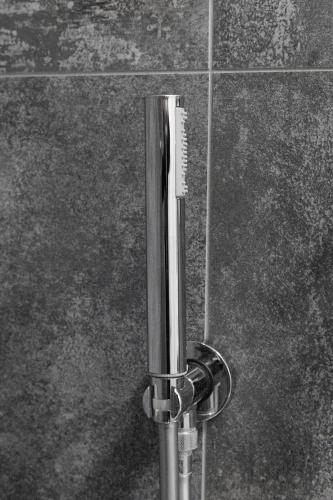 a metal pole with a comb on a tile wall at Residence Piazza Giotti 8 in Trieste