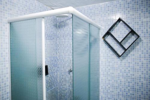 a glass shower in a bathroom with blue tiles at Barrudada Santarém in Santarém