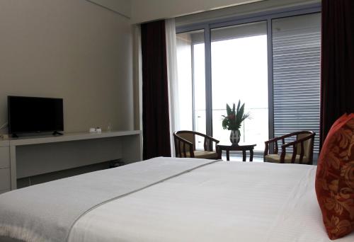 a bedroom with a large white bed and a television at Flow Hotel Benguela in Benguela