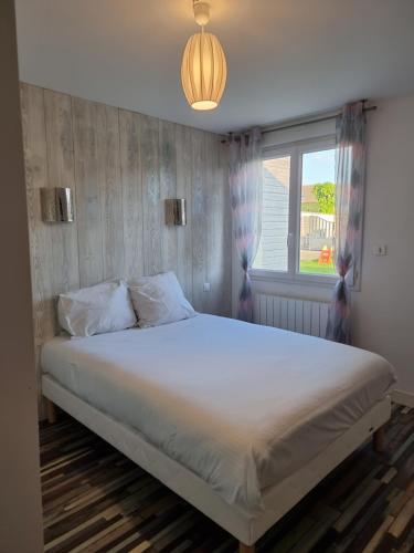 a bedroom with a large white bed with a window at Hôtel Bien Être La Palmeraie in Bénouville