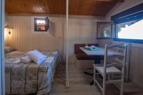 Camping Ria de Arosa 1 في بوبرا دو كارامينيال: غرفة نوم بسرير وطاولة وكرسي