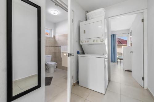 a bathroom with a white refrigerator and a mirror at Adele's Apartment with Pool, 5 minutes walk to the beach in Palm-Eagle Beach