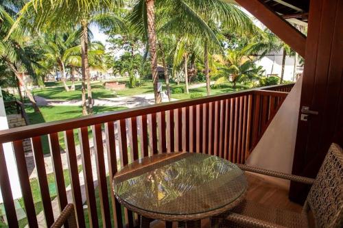 a table and chairs on a balcony with palm trees at Serrambi Resort in Porto De Galinhas