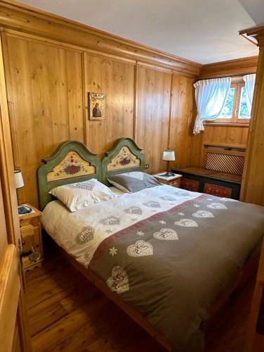 a bedroom with a bed in a room with wooden walls at Pecol Cozy Apartment R&R in Cortina dʼAmpezzo