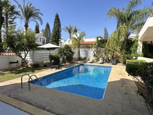 einen Pool in einem Garten mit Palmen in der Unterkunft Cheerful 3 bdr villa near the beach in Coral Bay