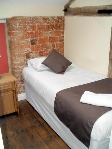 a bedroom with a bed with a brick wall at Rats Retreat at Tove Valley Cottages in Towcester