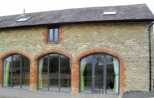 a brick building with three large glass windows at Rats Retreat at Tove Valley Cottages in Towcester