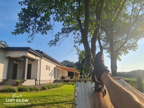 LOFT GILÓW Siedlisko Roztocze في Gilów: أقدام أشخاص على أرجوحة أمام المنزل