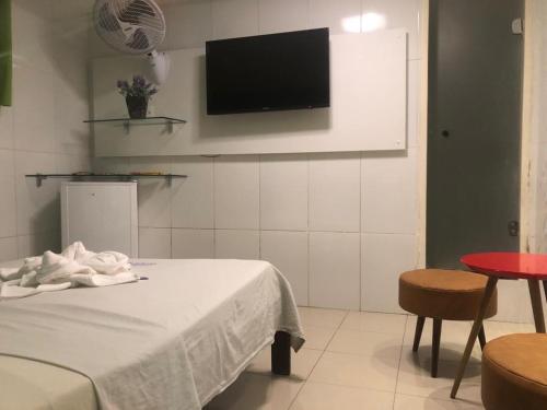 a room with a bed and a tv on the wall at Pousada Ybyrápuan in Campina Grande