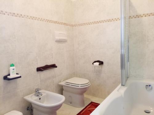 a bathroom with a toilet and a tub and a sink at Appartamento Che Vista! Affittacamere in Mombaroccio
