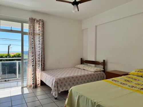 um quarto com 2 camas e uma grande janela em Vista Mar na Av. principal de Jacaraípe em Serra
