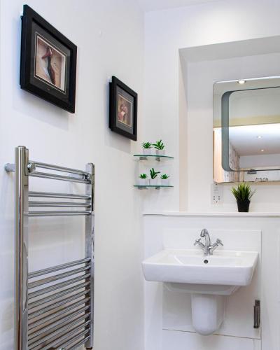 a white bathroom with a sink and a mirror at Luxury 3 King Bed Apartment Quayside in Manchester