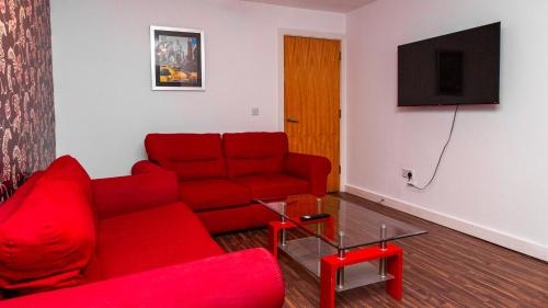 a living room with a red couch and a flat screen tv at Luxury 3 King Bed Apartment Quayside in Manchester