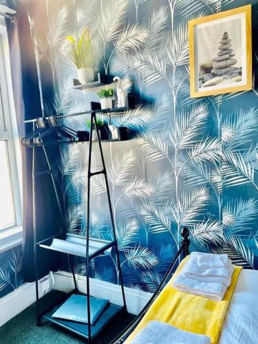 um quarto com uma parede azul com papel de parede de palmeira em Comfy 1 Bed Budget Apartment Near Blackpool City Centre 3 em Blackpool