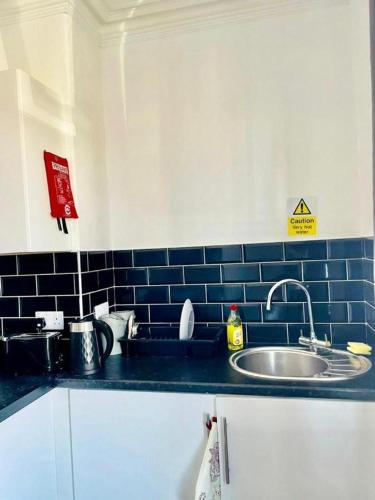 a kitchen with a sink and a blue tiled wall at Comfy 1 Bed Budget Apartment Near Blackpool City Centre 3 in Blackpool