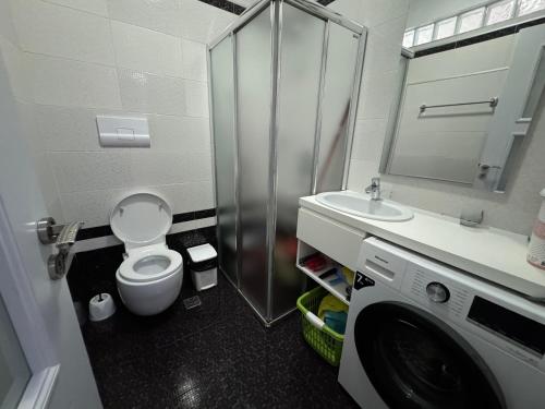 a bathroom with a toilet and a sink and a washing machine at Sunset Apartment in Vlorë