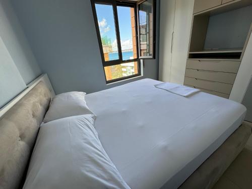 a large white bed in a room with a window at Sunset Apartment in Vlorë