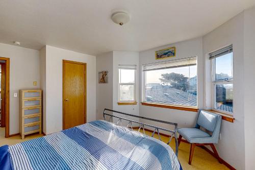 a bedroom with a bed and a chair and a window at Mermaid Beach House in Bandon
