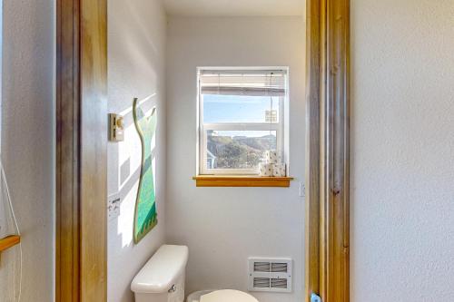 a bathroom with a toilet and a window at Mermaid Beach House in Bandon