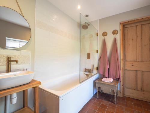 a bathroom with a tub and a sink and a mirror at Dryslwyn Rhydlewis in Troedyraur