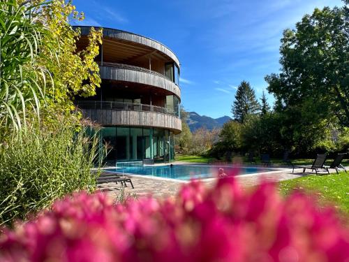 a building with a swimming pool and pink flowers at Gesundhotel Bad Reuthe in Vorderreuthe