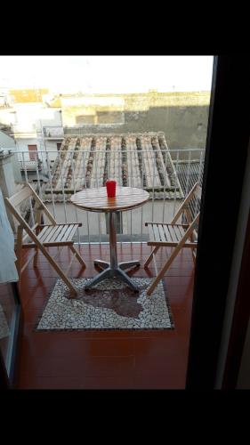 un tavolo con sedie e una tazza rossa sul balcone di Da zia Franca ad Acate