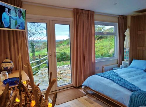 a bedroom with a bed and a large window at Sea Moss Cabin in Tywyn