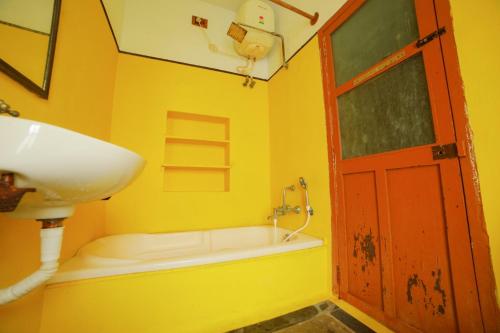 a yellow bathroom with a sink and a red door at Sai White Villa Pondicherry in Puducherry