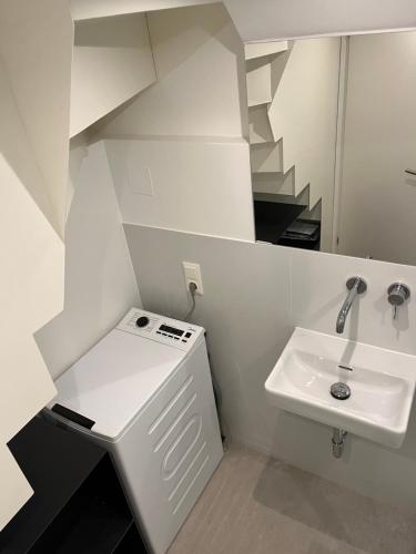 a white bathroom with a sink and a staircase at Business City Lodge in Sankt Pölten