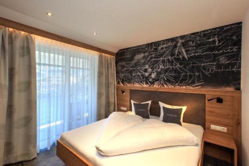 a bedroom with a bed with a chalkboard on the wall at Apart Lutz in Prutz