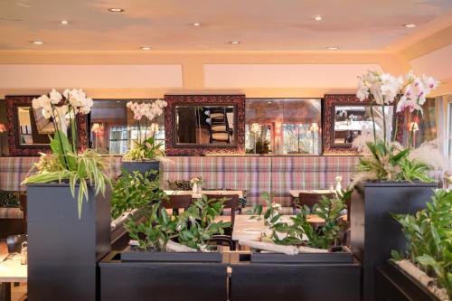 a restaurant with tables and potted plants at Hotel Parc Plaza in Luxembourg