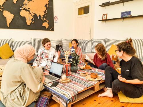 Ithaka Hostel في الإسكندرية: مجموعة من النساء يجلسون حول طاولة مع جهاز كمبيوتر محمول