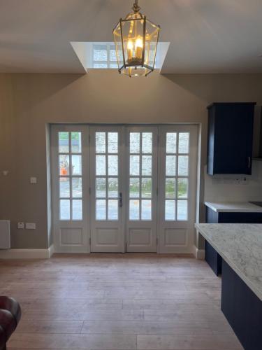 a kitchen with white doors and a chandelier at Rokeby cottage in Drogheda