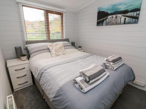 a bedroom with a bed with towels on it at Tree View Lodge in Windermere