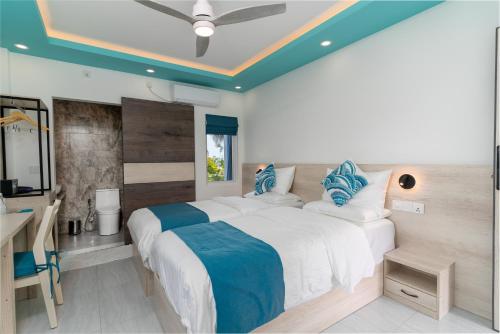 a bedroom with two beds with blue pillows at Ukulhas Sands in Ukulhas
