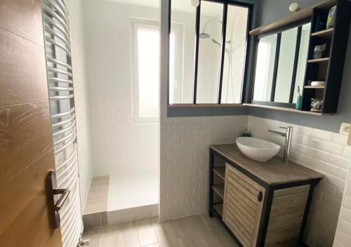ein Bad mit einem Waschbecken und einem Spiegel in der Unterkunft Chez Célina - La Conciergerie. in Buxerolles