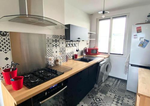 eine Küche mit einem Herd, einer Spüle und einem Kühlschrank in der Unterkunft Chez Célina - La Conciergerie. in Buxerolles