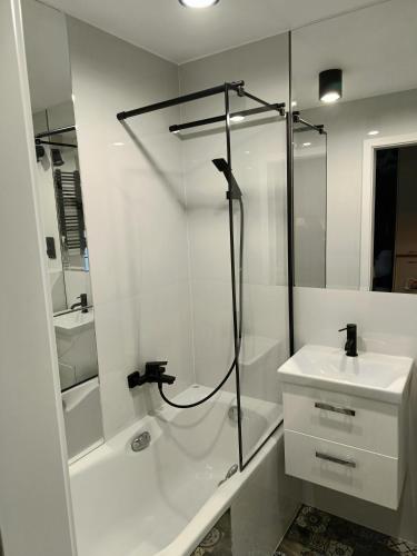 a white bathroom with a shower and a sink at Apartament Chopina 5 m5 - Centrum Sopotu 3 min do Monciaka in Sopot