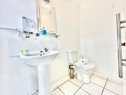 a white bathroom with a sink and a toilet at Watch Cottage in Brook