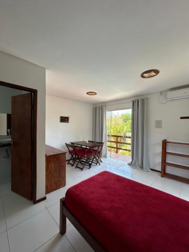 a bedroom with a red bed and a table with chairs at Pousada Recanto Pontal de Maracaipe in Porto De Galinhas