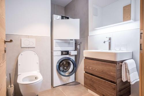 a bathroom with a toilet and a sink and a washing machine at Apartment Walt 3.5 - GRIWA RENT AG in Grindelwald