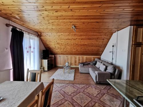 a living room with a couch and wooden ceiling at Júlia Apartman in Balatonalmádi