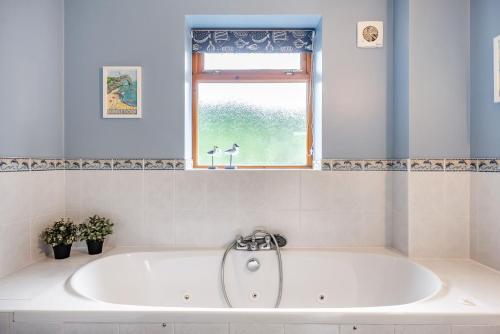 a bath tub in a bathroom with a window at Treetops in Wimborne Minster