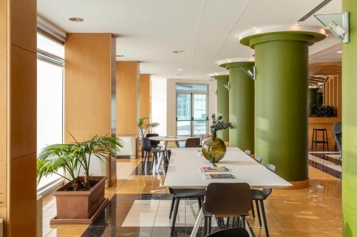 una oficina con columnas verdes, mesas y sillas en B&B HOTEL Cuneo Cristal, en Cuneo