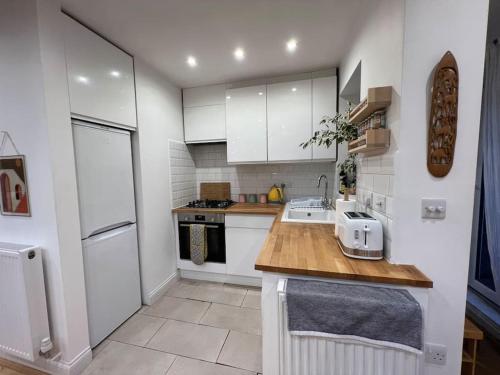 a kitchen with white cabinets and a wooden counter top at Sunny London Garden Apartment in London