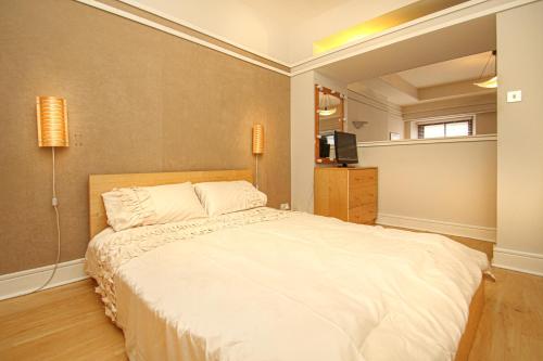 a bedroom with a large white bed and a television at Stylish Merchant City Apartment in Glasgow