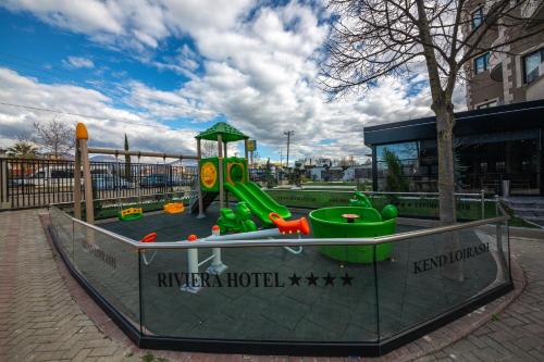 a playground with a green slide in front of a building at Hotel Riviera in Tirana