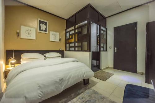 Schlafzimmer mit einem großen weißen Bett mit einem Kopfteil aus Holz in der Unterkunft VDR Hotel in Douala