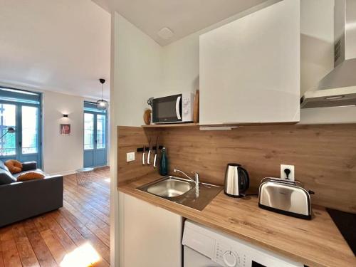 une cuisine avec des armoires blanches et un évier dans l'établissement Beau Studio rue du Printemps, à Toulouse